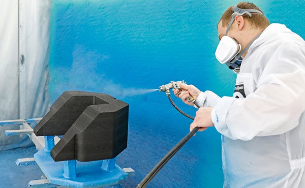 Op de afbeelding past een medewerker van IFG een coating toe in een spuitruimte.